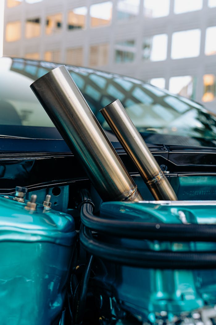 Detailed shot of a modern car engine with shiny chrome pipes and teal components.