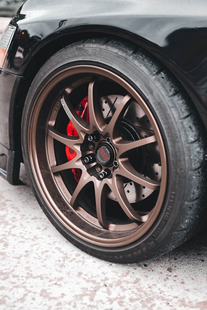 Detailed view of a modern car wheel featuring a bronze alloy rim and red brake caliper.